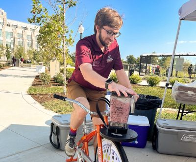Student riding a blender bike at sustainable transportation fair